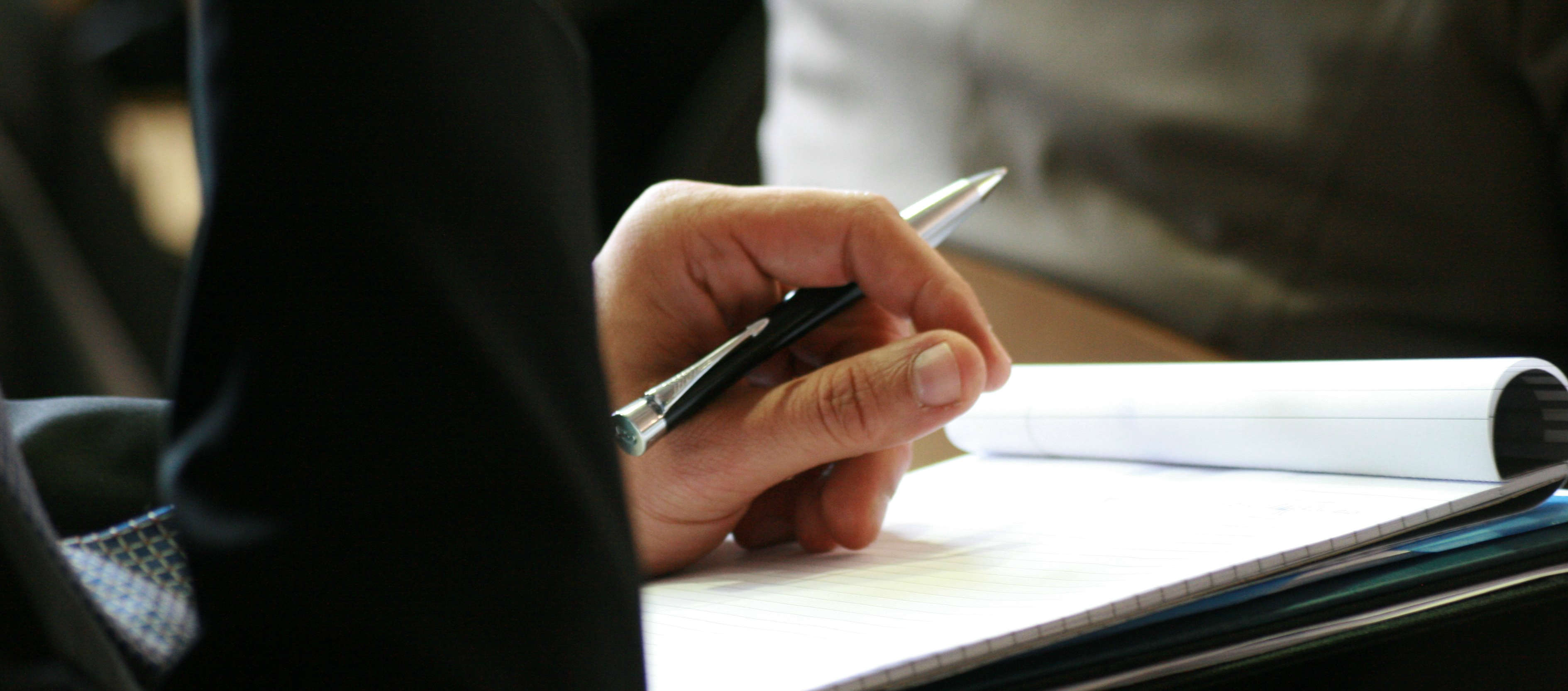 An image of a hand holding a pen and paper.