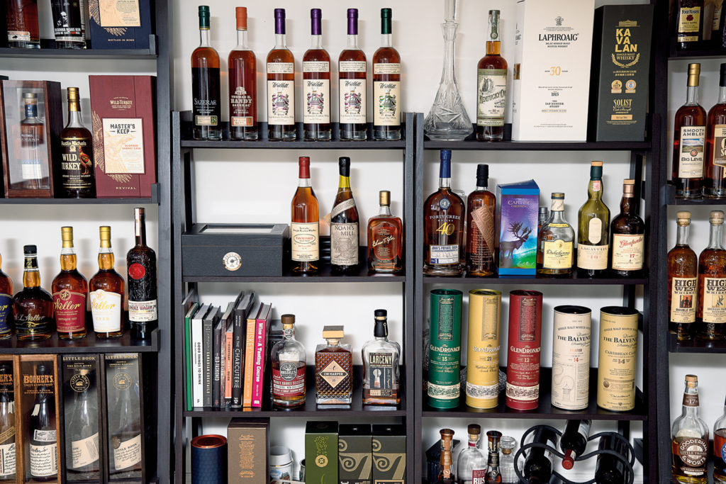 An up-close image of four tall shelves with many neatly displayed whiskey bottles lining them