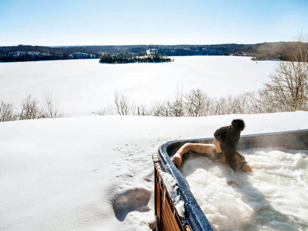 Person in an outdoor hot tub overlooking the frozen Wolfe Lake
