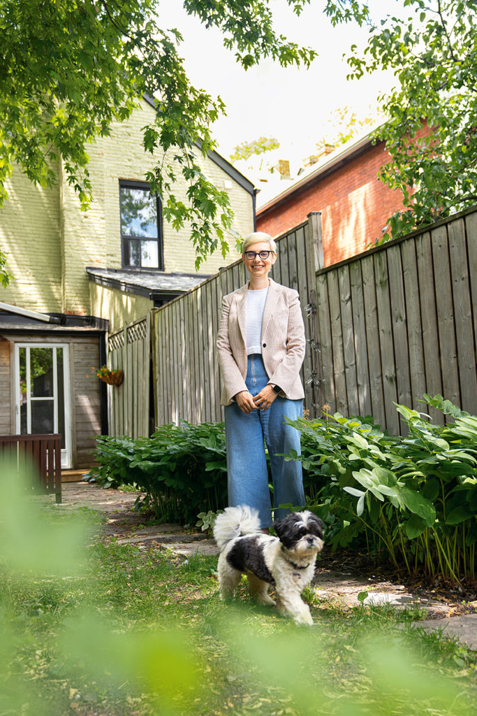 Hilary Book stands in her leafy backyard with her Shih Tzu, Leora