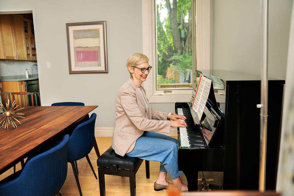 Hilary Book sitting playing the piano in her west-end home