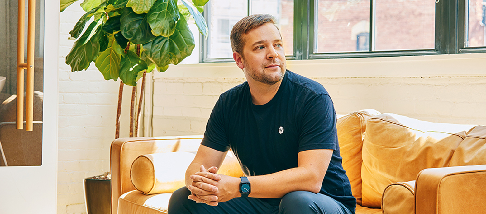 Evan Thomas sits on a leather couch at the Wealthsimple office